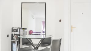 Une pièce comprenant une table ronde en verre et quatre chaises, un distributeur d’eau, une porte et un miroir au mur.