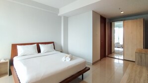 Een moderne hotelkamer met een groot bed, een houten hoofdeinde en uitzicht op de gang en de badkamer.