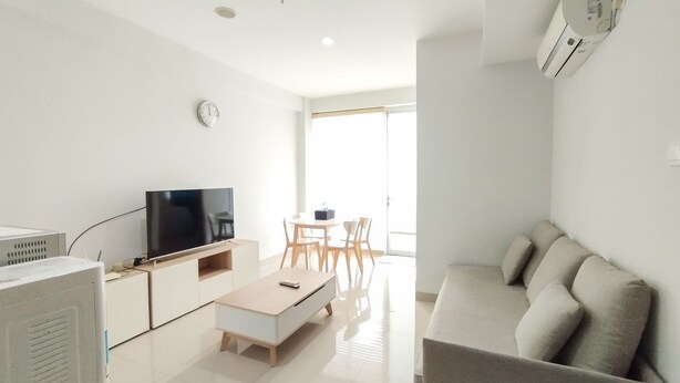 Een moderne woonkamer met een flatscreen-tv, een salontafel, een bank en een eethoek met stoelen en een tafel.