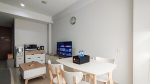Een moderne keuken met een eethoek, met een witte tafel, stoelen en een zwarte doos met waterflessen.