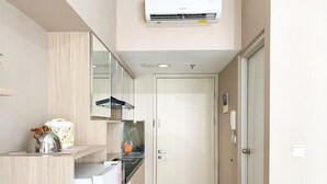 Una cocina compacta equipada con microondas, hervidor de agua y dispensador de agua. Una puerta da acceso a otra habitación.