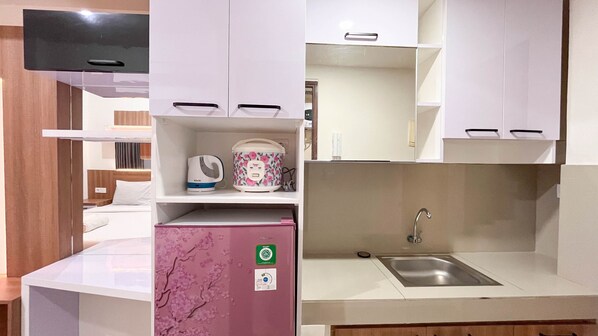 Une petite cuisine équipée comprenant un réfrigérateur encastré, un évier et un four à micro-ondes.