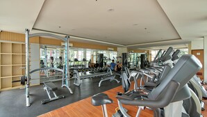 A gym with various exercise equipment, including treadmills, weight machines, and free weights. - Scenic Studio Room Apartment Vida View Makassar (Makassar)