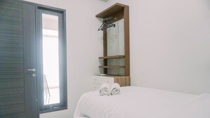 A bedroom with a bed, a wooden shelf with a mirror, and a window. - Best Deal And Modern 2Br Amazana Serpong Apartment (South Tangerang)