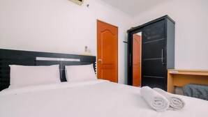 Una habitación de hotel con una cama, una puerta de madera y un armario negro con texto.