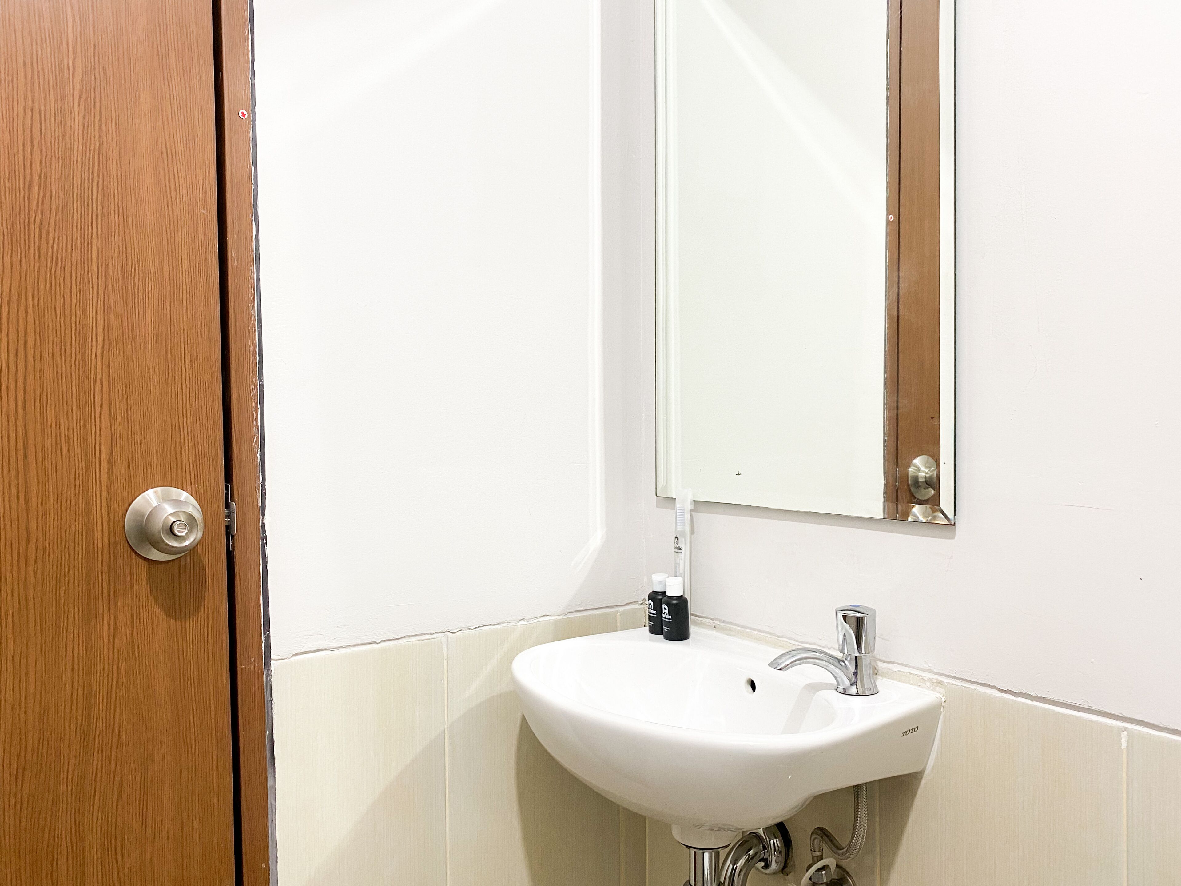 A bathroom with a wooden door, a white sink, and a mirror.