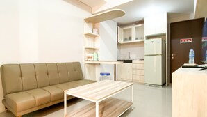 A modern living room with a sofa and a wooden coffee table. - Comfort 2Br At Transpark Juanda Bekasi Timur Apartment (Bekasi)