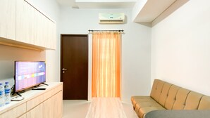 A compact room with a wooden cabinet, a television, a sofa, and a curtain. - Comfort 2Br At Transpark Juanda Bekasi Timur Apartment (Bekasi)