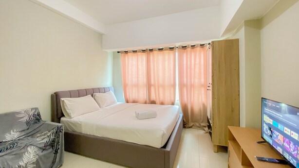 Ein Schlafzimmer mit einem Bett, einem Fernseher und einem Holzschrank.