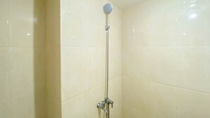 Ein Badezimmer mit Dusche, gefliesten Wänden und einer Deckenleuchte.