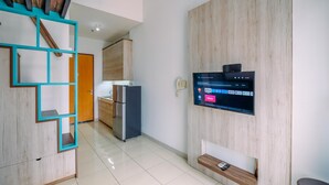 A modern kitchen with a built-in TV, wooden cabinets, and a teal-framed shelving unit. - Best Homey And Cozy Studio At Dave Apartment (Depok)