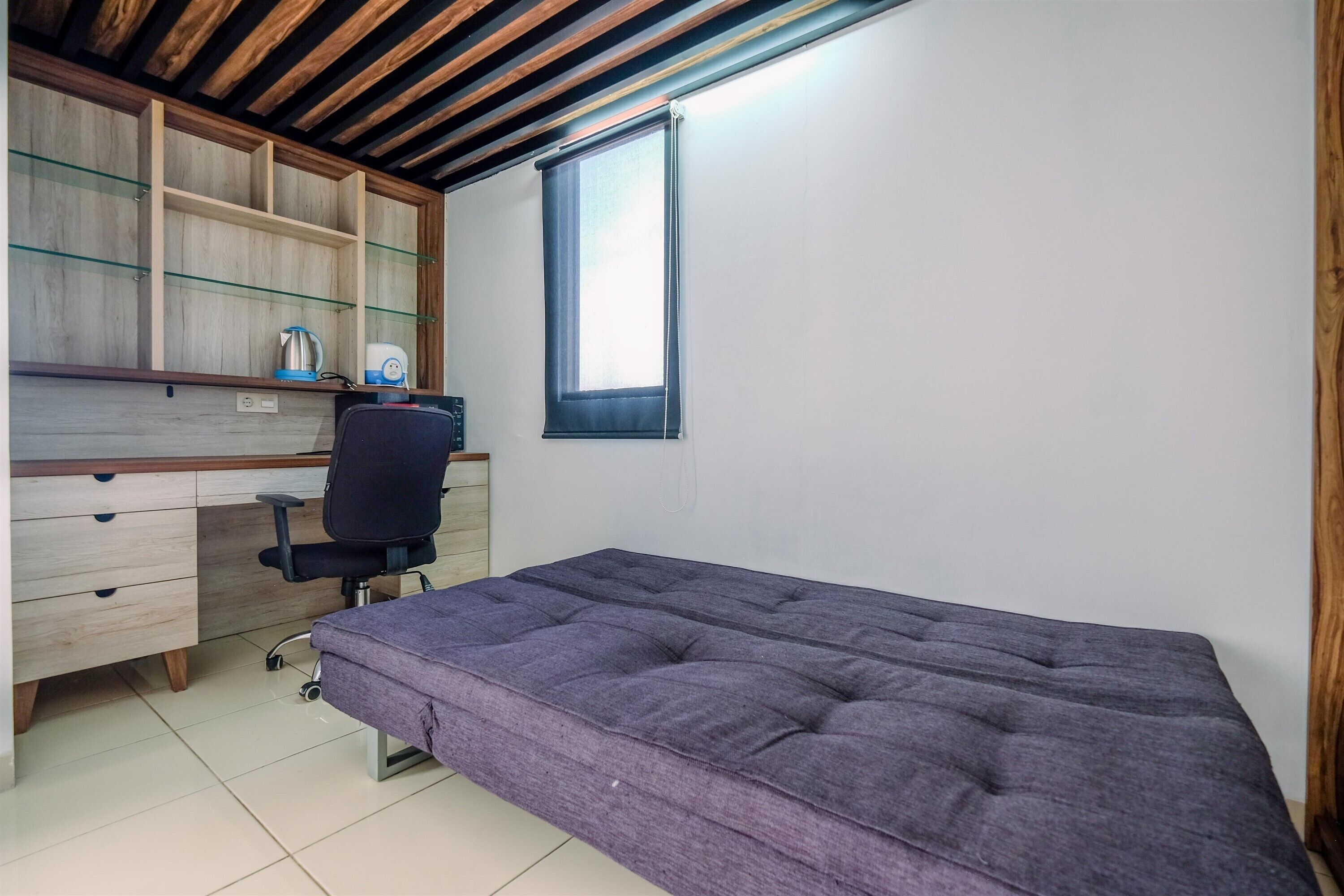 A bedroom with a bed, a desk, and a chair.