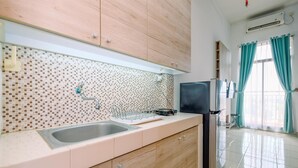 A modern kitchen with a tiled backsplash, a stainless steel sink, wooden cabinets, and a built-in refrigerator. - Best Homey And Cozy Studio At Dave Apartment (Depok)