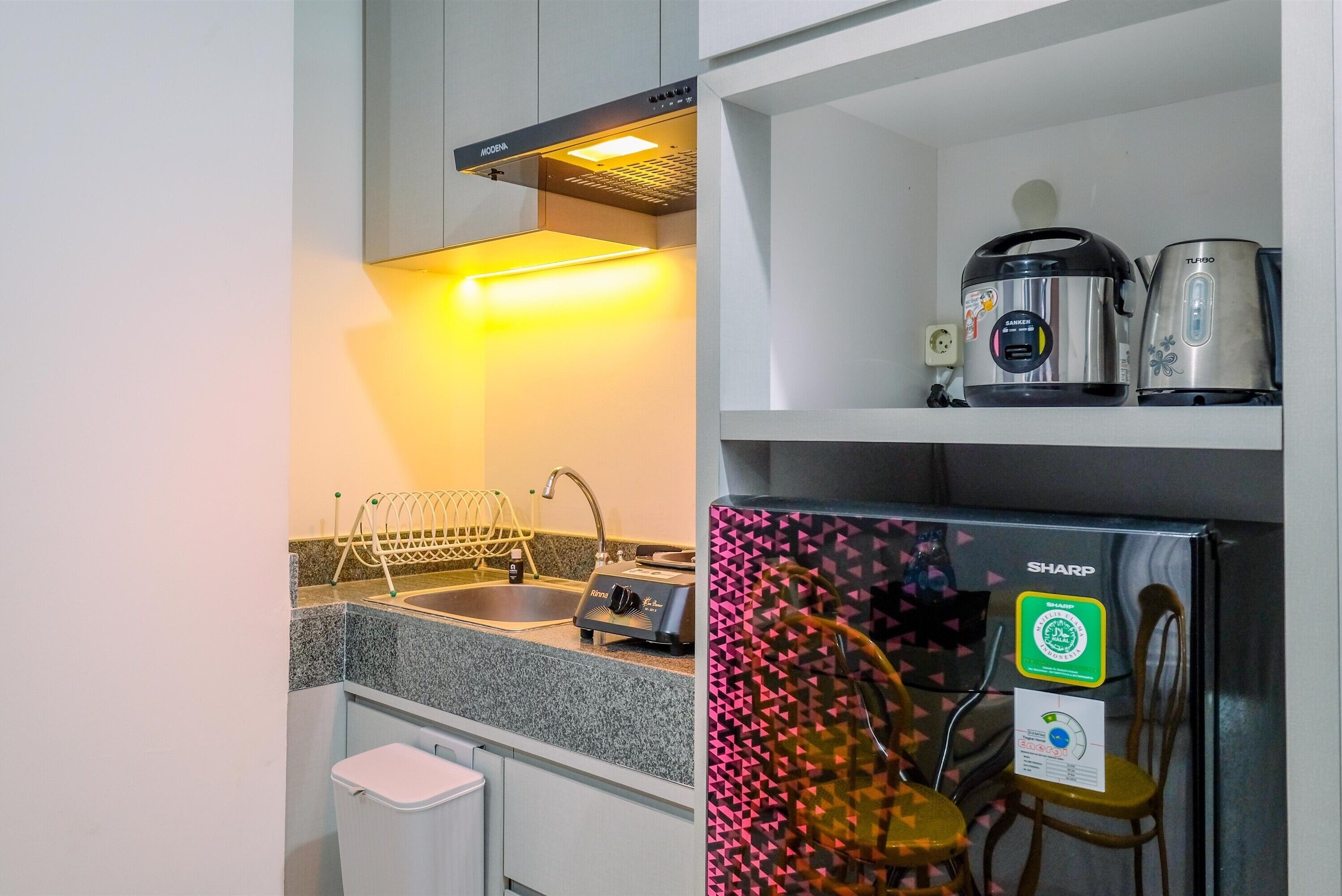 A compact kitchen with a built-in oven, a kettle, and a coffee maker on the countertop.