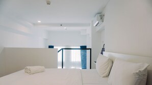 A hotel room with a neatly made bed, a wall-mounted air conditioner, and a view of the hallway. - Comfortable And Homey Studio Loft At Kingland Avenue Apartment (South Tangerang)