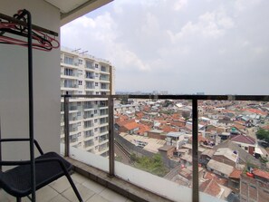 Un balcon offrant une vue sur une zone urbaine densément peuplée, avec de nombreux immeubles et une variété de toits.