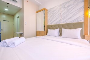 A hotel room with a bed, a large mirror, and a marble wall. - Warm And Cozy Studio At Tokyo Riverside Pik 2 Apartment (Teluknaga)