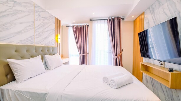 Ein Hotelzimmer mit einem großen Bett, einem Fernseher und einer Marmorwand.