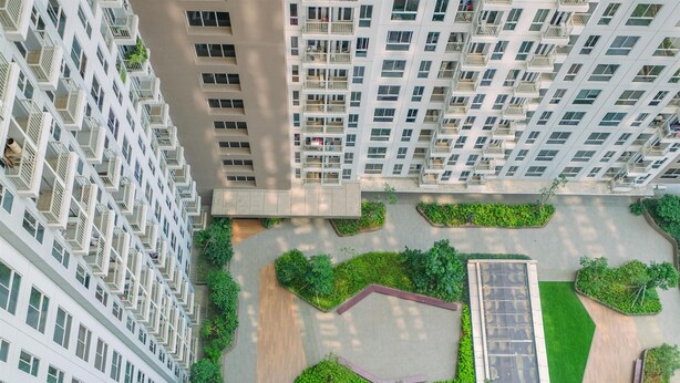A high-rise residential building with multiple balconies and a landscaped courtyard with pathways and greenery. - Well Furnished And Restful Studio Tokyo Riverside Pik 2 Apartment (Teluknaga)