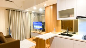 A modern kitchen with a built-in stove, a sink, and a flat-screen TV. - Comfy and Modern Look 1BR LRT City Jatibening Apartment (Bekasi)