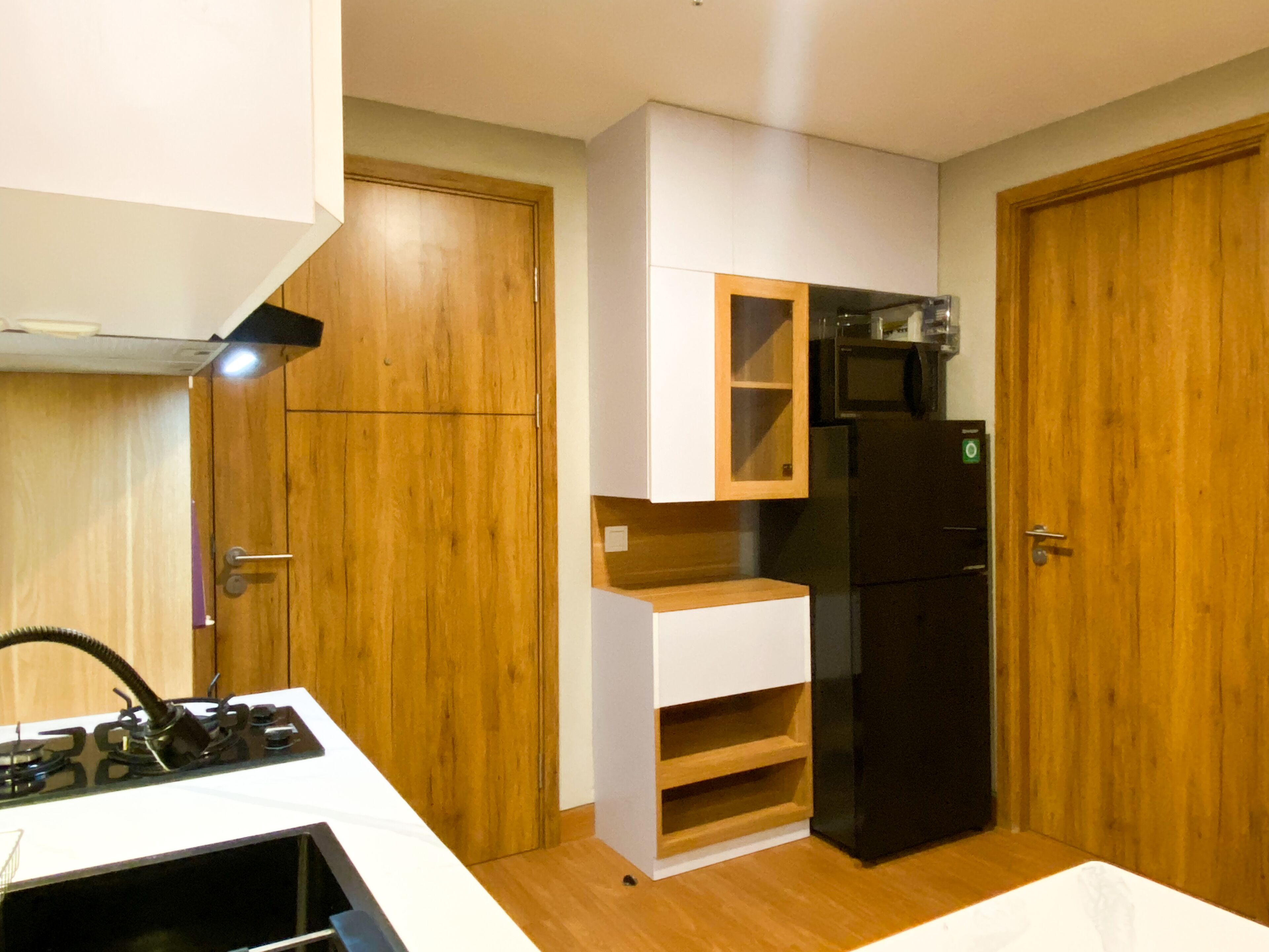 A compact kitchen with wooden cabinets, a black refrigerator, and a microwave.