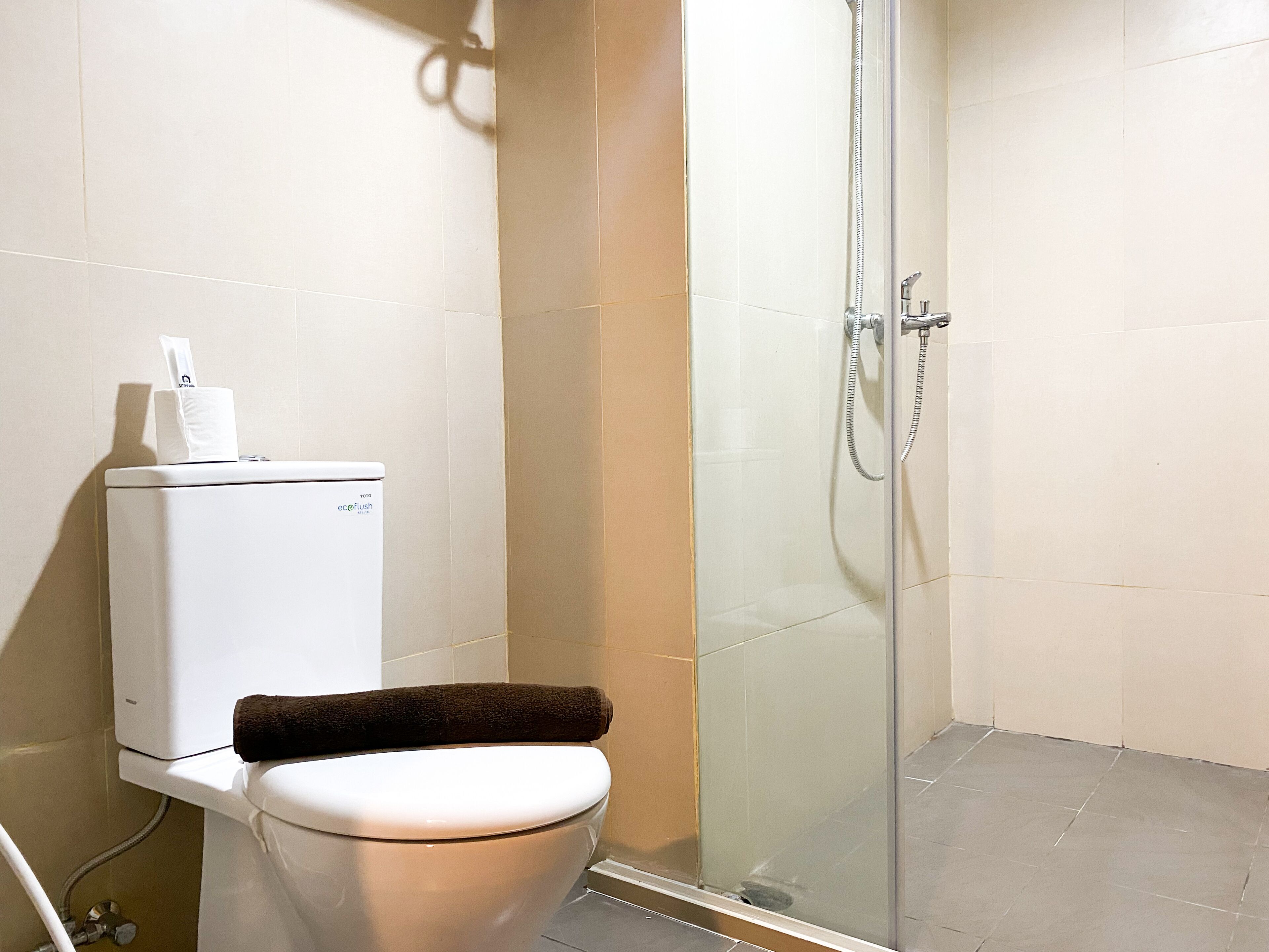 Une salle de bain avec des toilettes, une douche à parois de verre et une serviette posée sur les toilettes.
