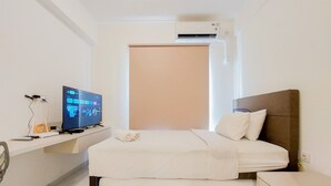 Quarto de hotel com cama, televisão, secretária e ar condicionado.