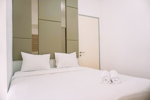 A hotel room with a bed, two pillows, and rolled towels on the bed. - Modern And Homey 2Br Apartment At M-Town Residence (Gading Serpong)