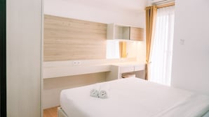 Ein Hotelzimmer mit Bett, Holzwand, weißem Schreibtisch und einem Fenster mit Vorhängen.