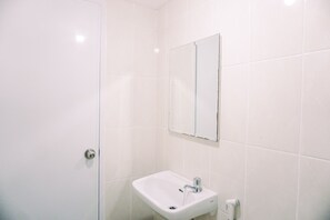 A bathroom with white tiles, a sink, a mirror, and a door. - Modern And Homey 2Br Apartment At M-Town Residence (Gading Serpong)
