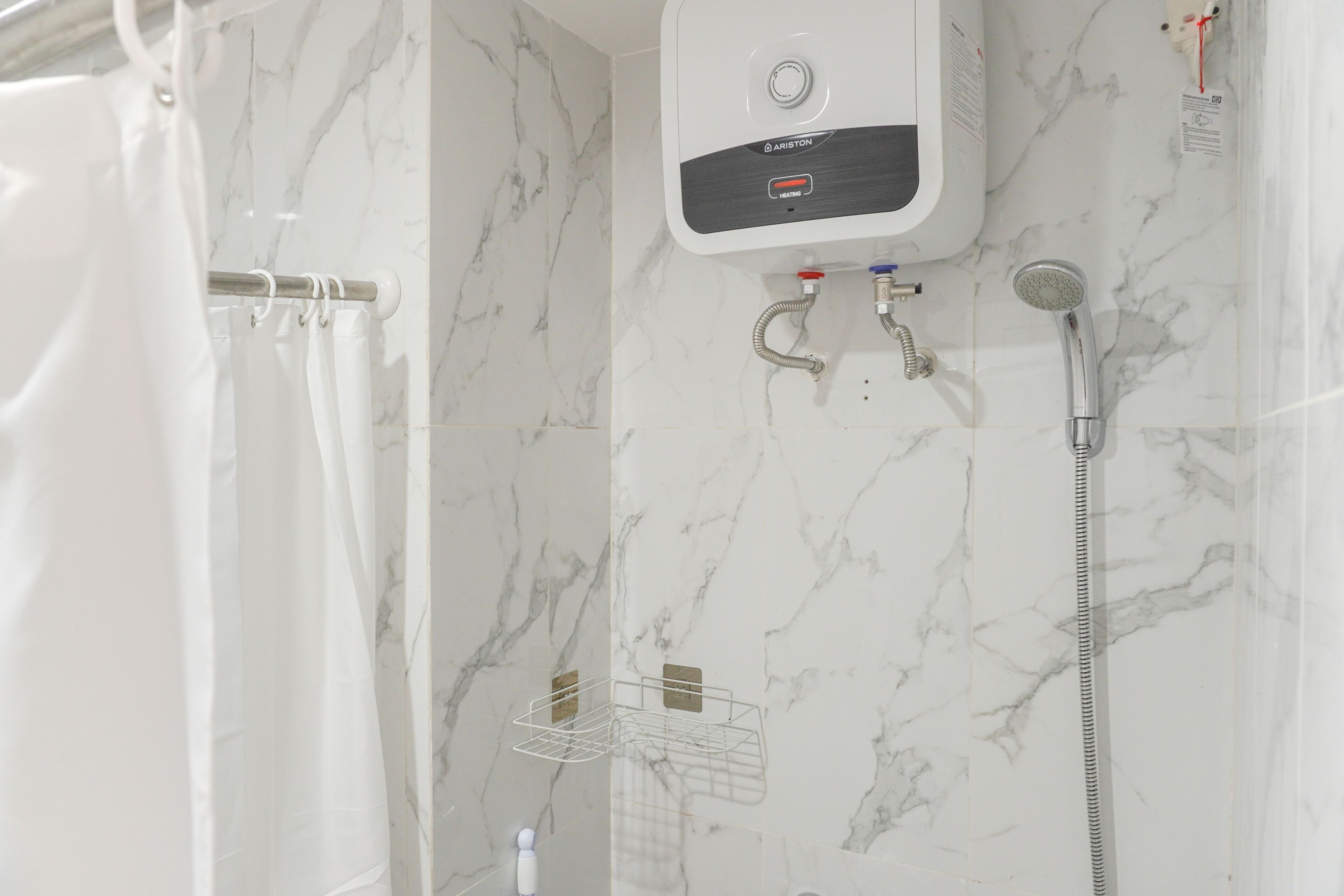 A modern bathroom with a white shower enclosure, a wall-mounted heater, and a handheld showerhead.