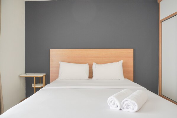 Relax in a serene space with a large bed, nightstand, and mirror.