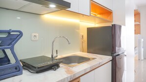 A modern kitchen with a built-in stove, sink, and stainless steel refrigerator. - Good Choice Studio Apartment Anwa Residence Bintaro (South Tangerang)