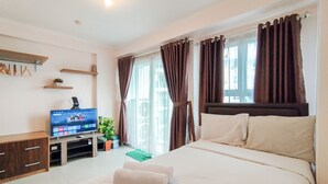 Une chambre d’hôtel avec un lit, une télévision, une petite table et une fenêtre avec des rideaux.