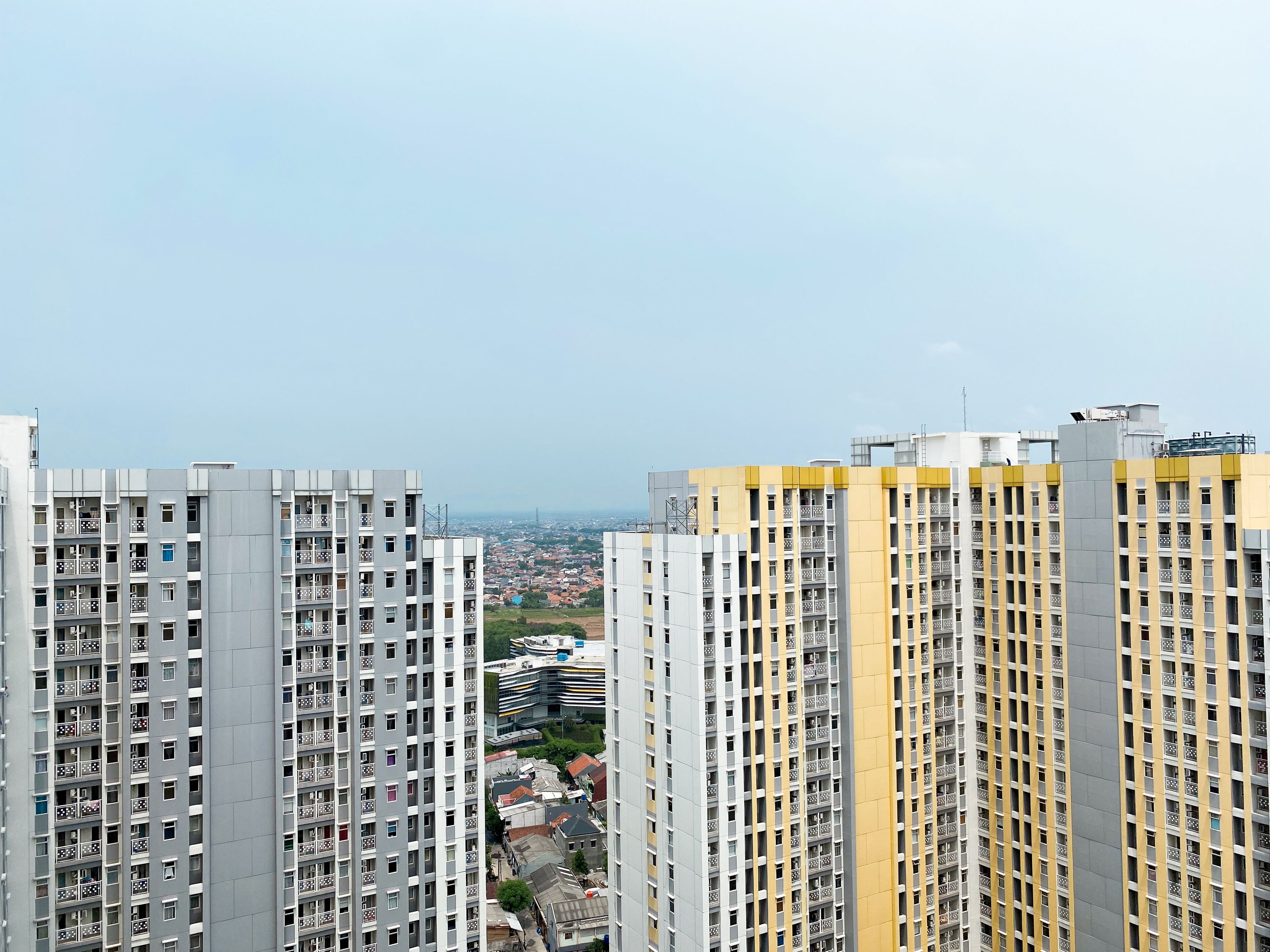 Un immeuble résidentiel de grande hauteur, doté de nombreux balcons et offrant une vue sur le paysage urbain en arrière-plan.