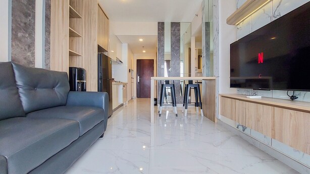 Una sala de estar moderna con un sofá gris, un televisor de pantalla plana grande y un mueble de televisión de madera.