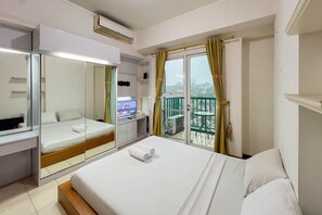 A hotel room with a bed, a TV, a desk, and a balcony with a view. - Cozy 1Br At Marbella Suites Dago Pakar Bandung Apartment (Bandung)