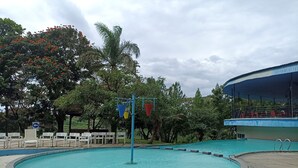 A circular pool with a surrounding walkway, white chairs, and a covered seating area with red chairs. - Cozy 1Br At Marbella Suites Dago Pakar Bandung Apartment (Bandung)