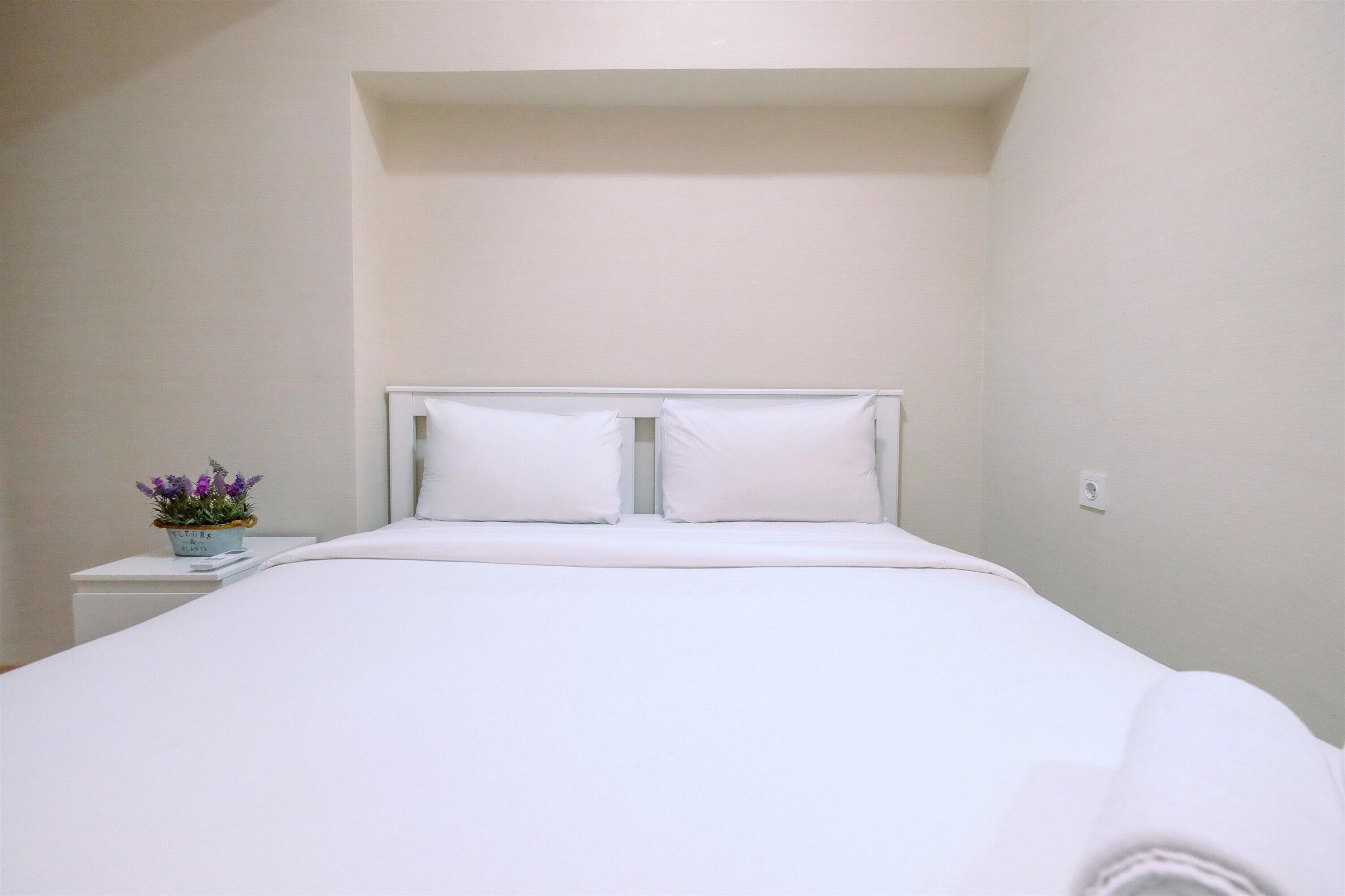 Un letto rifatto con cura in una stanza dal semplice arredamento bianco.