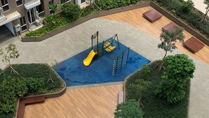 Ein Spielbereich für Kinder mit Rutsche und Klettergerüsten, umgeben von Grünflächen und einer Holzterrasse.