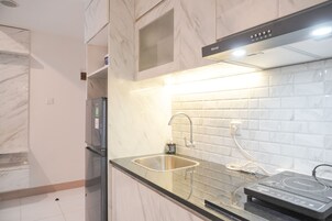 Una cocina moderna con un lavamanos de acero inoxidable, horno empotrado y una salpicadera de mármol.