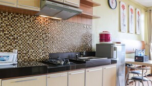 A modern kitchen with a tiled backsplash, stainless steel appliances, and wooden cabinets. - Spacious Studio The Edge Bandung Apartment (Cimahi)