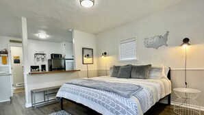Une chambre moderne avec un grand lit, un bureau et un coin cuisine.