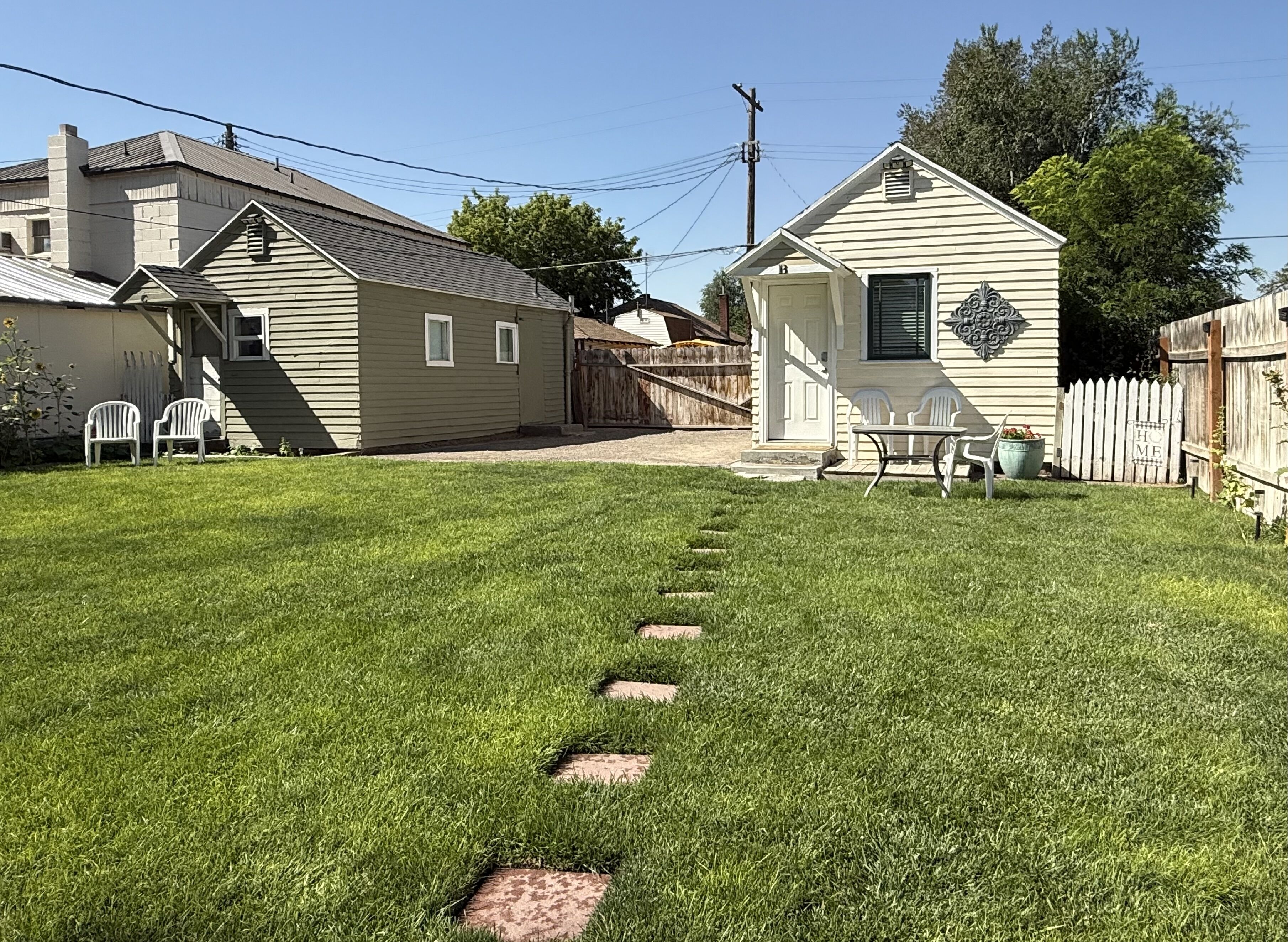 A residential property with a well-maintained lawn, a wooden deck, and a small house with a porch.