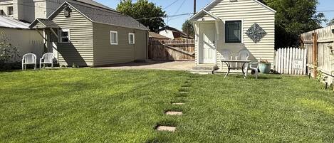 A residential property with a well-maintained lawn, a wooden deck, and a small house with a porch.