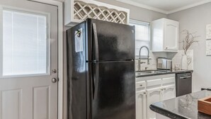 A kitchen with a black refrigerator, white cabinets, a sink, and a dishwasher. - Charming two ensuites near hospitals & shops. Jefferson Hwy•Bluebonnet (Baton Rouge)