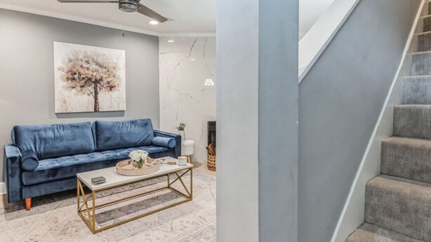 A living room with a blue sofa, a coffee table, and a ceiling fan. - Charming two ensuites near hospitals & shops. Jefferson Hwy•Bluebonnet (Baton Rouge)