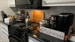 A kitchen with a coffee and tea bar, a kettle, a coffee maker, and various kitchen utensils. - Charming two ensuites near hospitals & shops. Jefferson Hwy•Bluebonnet (Baton Rouge)