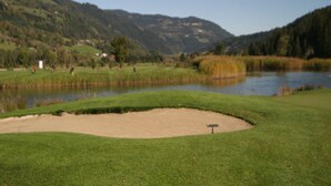 A golf course with a pond, sand bunkers, and a backdrop of hills. - Chalet in Stadl an der Mur near Ski Slopes (Stadl an der mur)