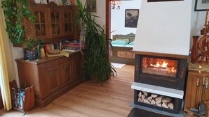 A cozy living room with a fireplace, wooden cabinets, and a dining area.